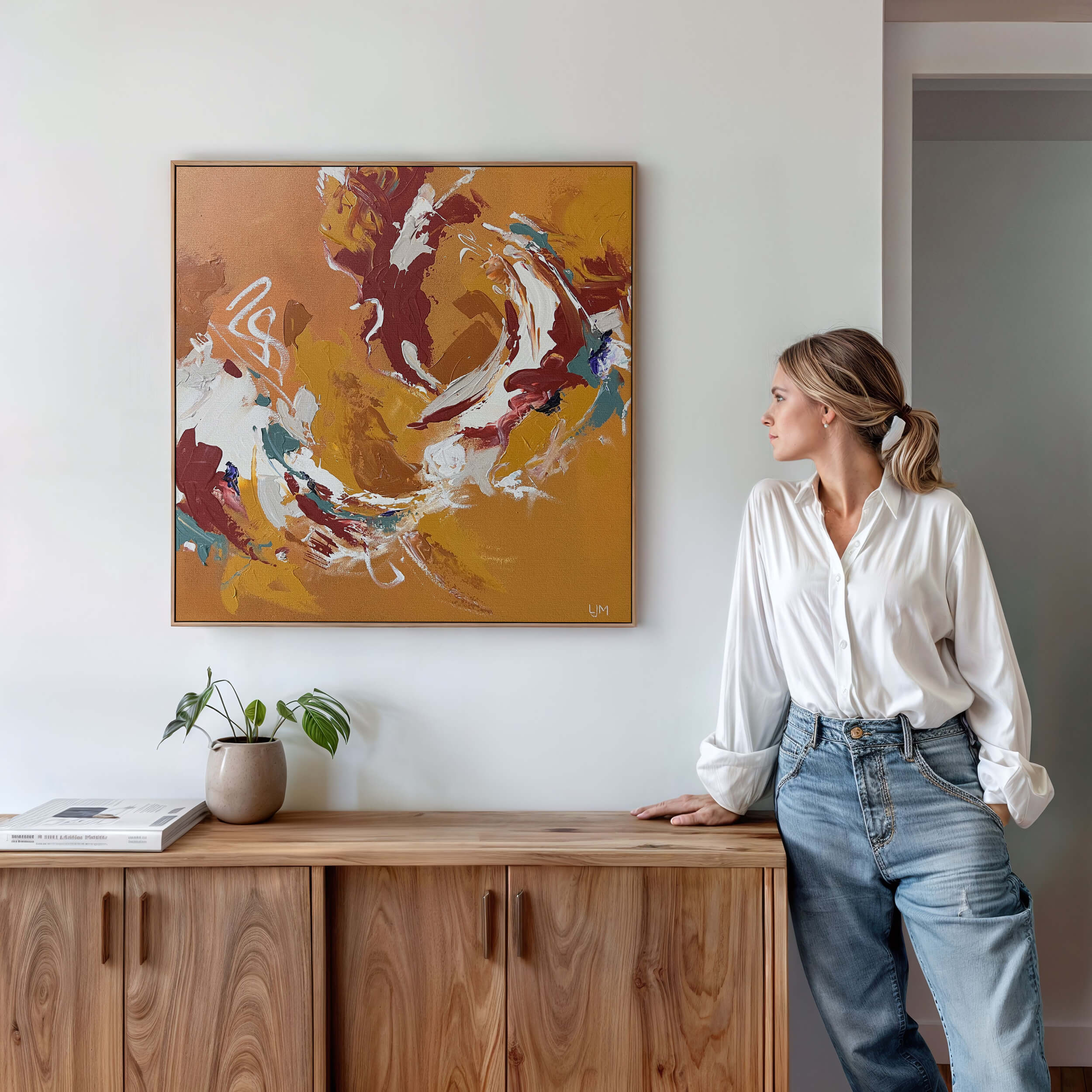 Woman staring at a medium golden abstract art by Lee J Morgan displayed on a living room wall