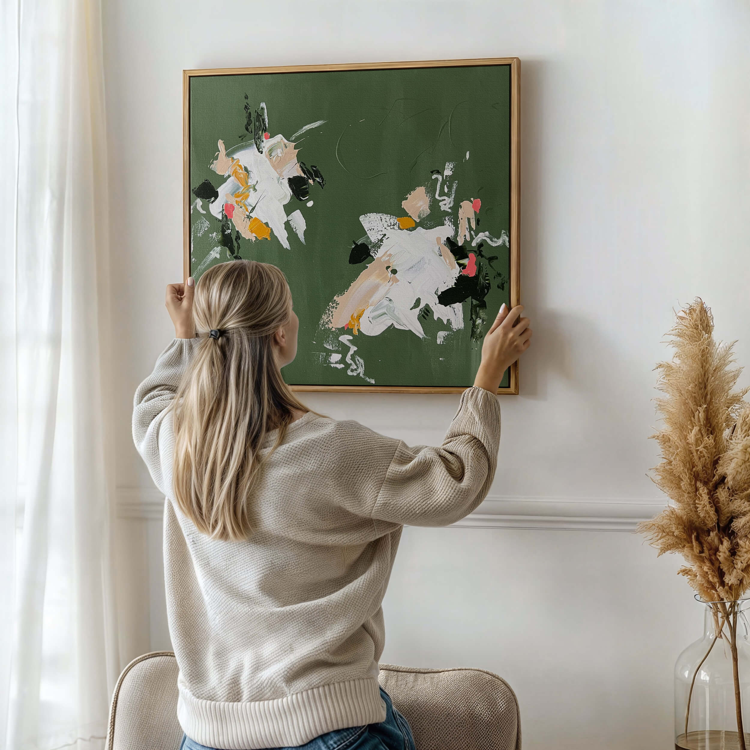 Woman hanging a medium green abstract art by Lee J Morgan on a wall